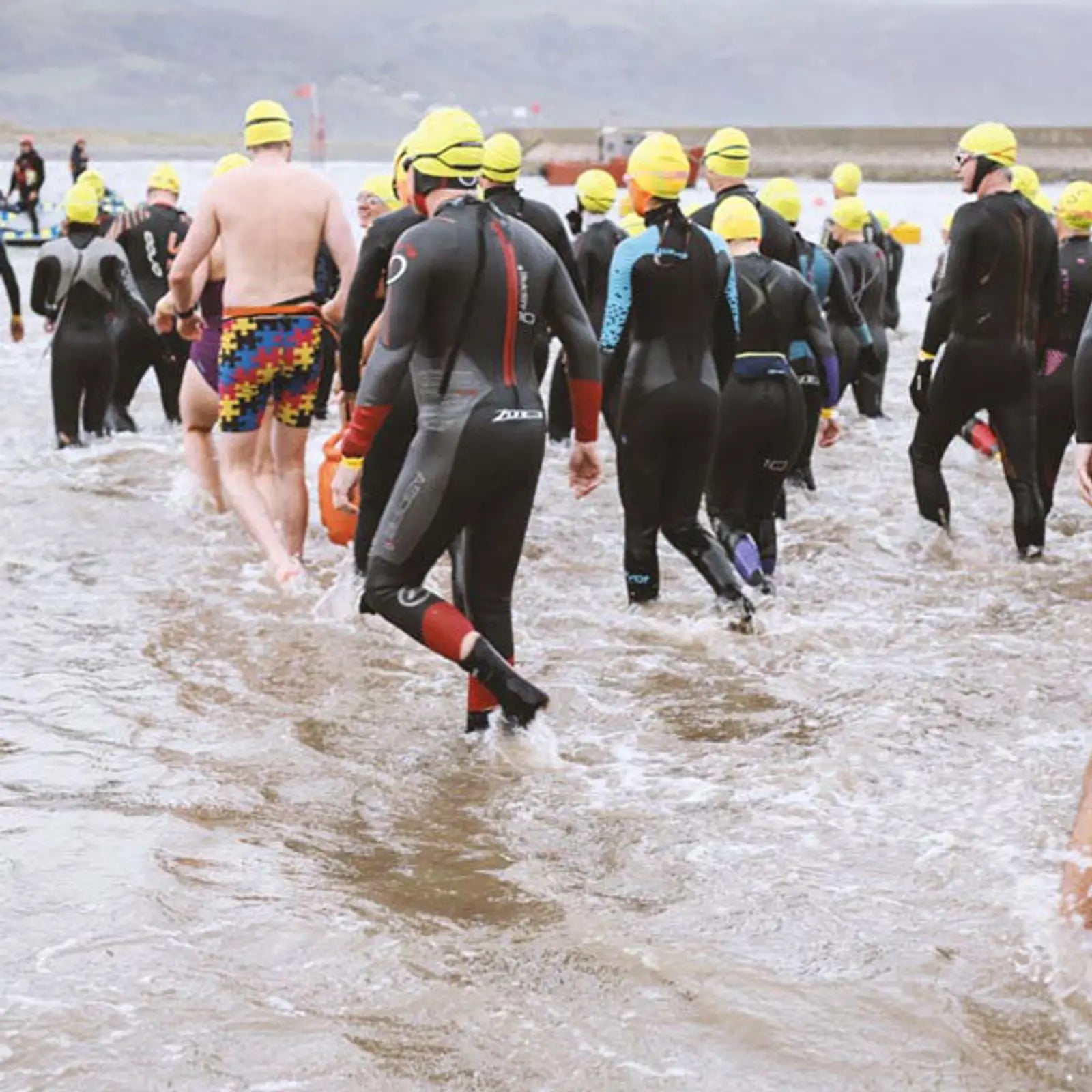 A group of people walking into the sea to go swimming