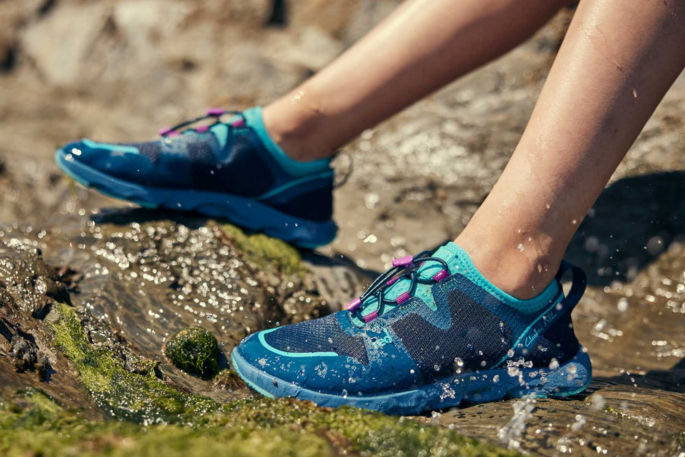 Blue aqua shoes against beach rocks