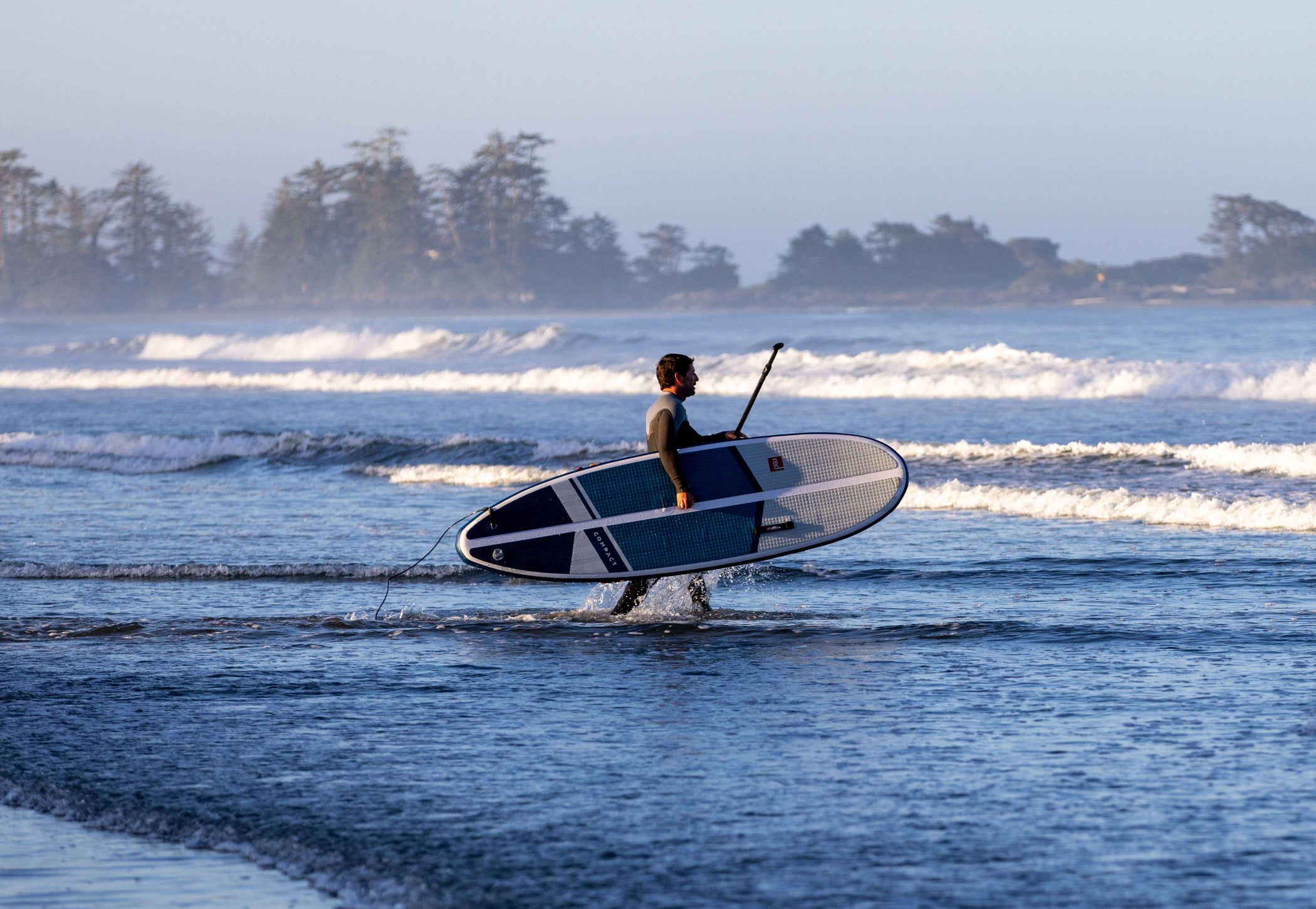 man entering the sea with inflatable paddle board