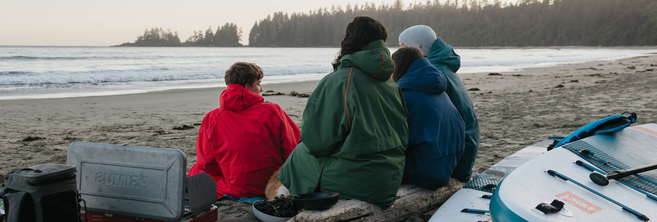 a family sat on the beach in red changing robes