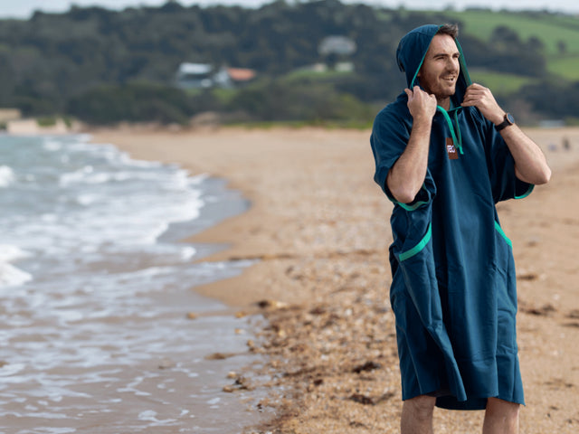 A man wearing the Quick Change Robe on the beach