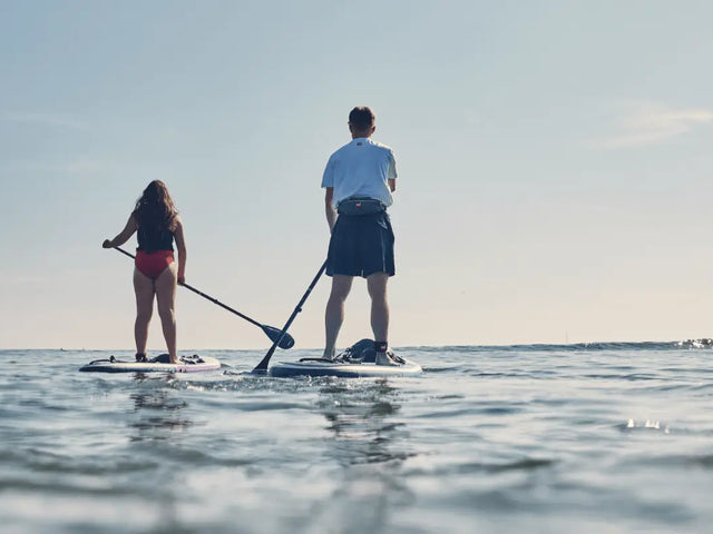two people paddleboarding towards horizon
