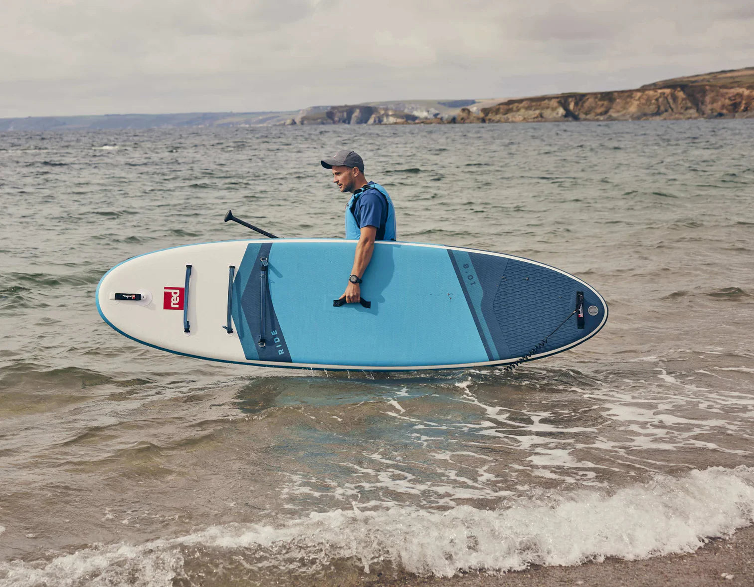 A man carrying his paddleboard into the ocean
