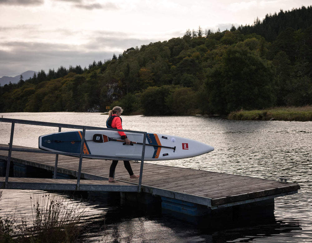 woman entering the water with elite racing paddle board