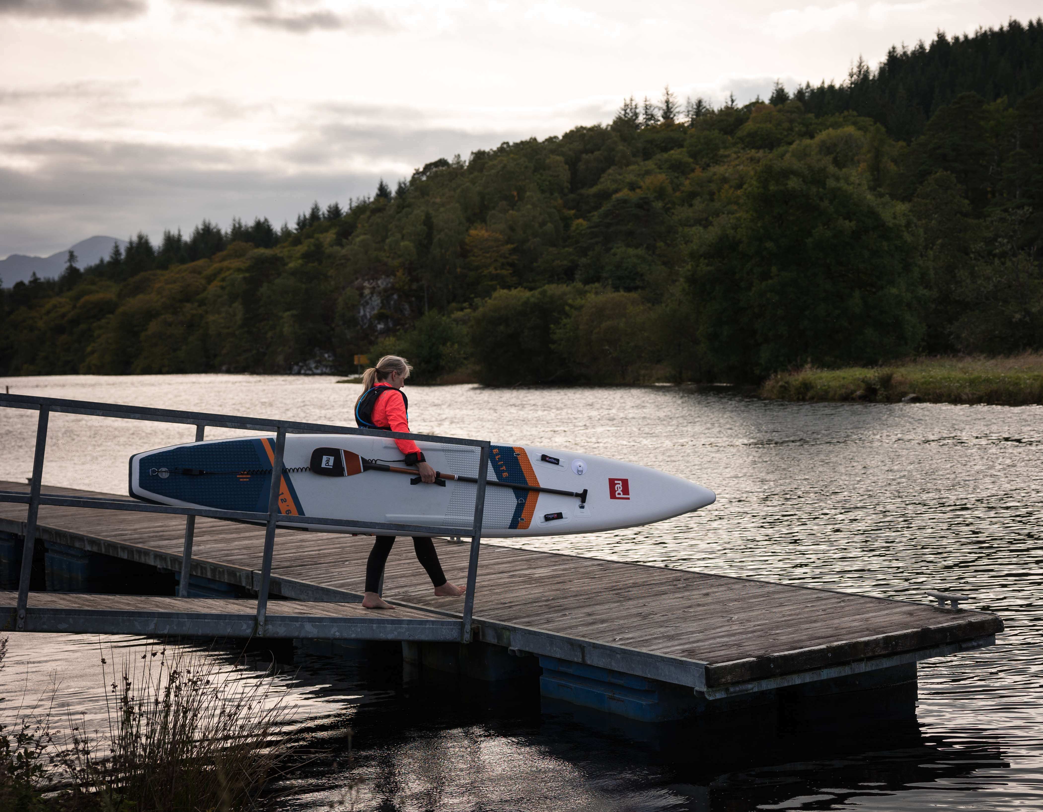 woman entering the water with elite racing paddle board