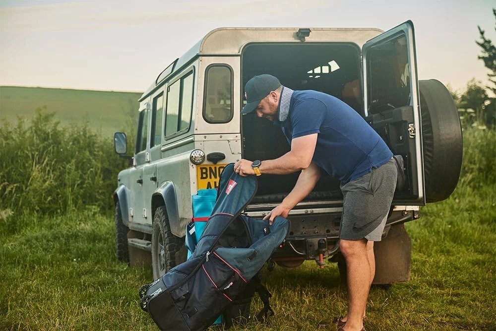 Man by his car getting paddleboard out of ATB SUP Carrier