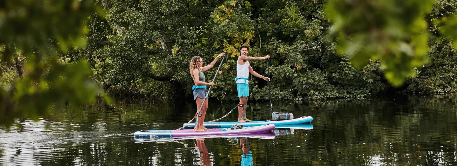 2 people stood up paddleboarding in a river