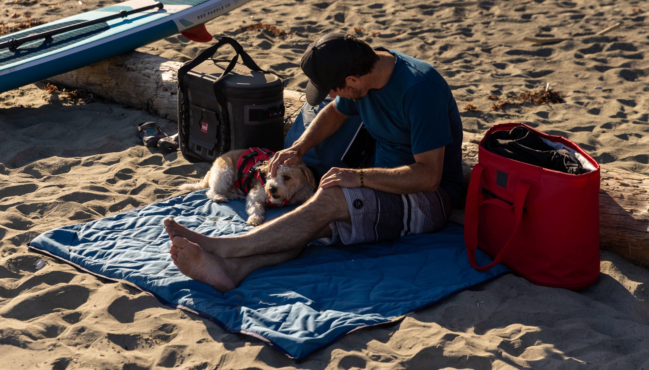 man sat on red adventure waterproof blanket on beach