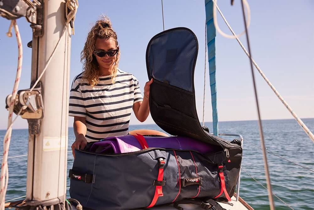 woman storing paddle board in a paddle board bag on a boat deck