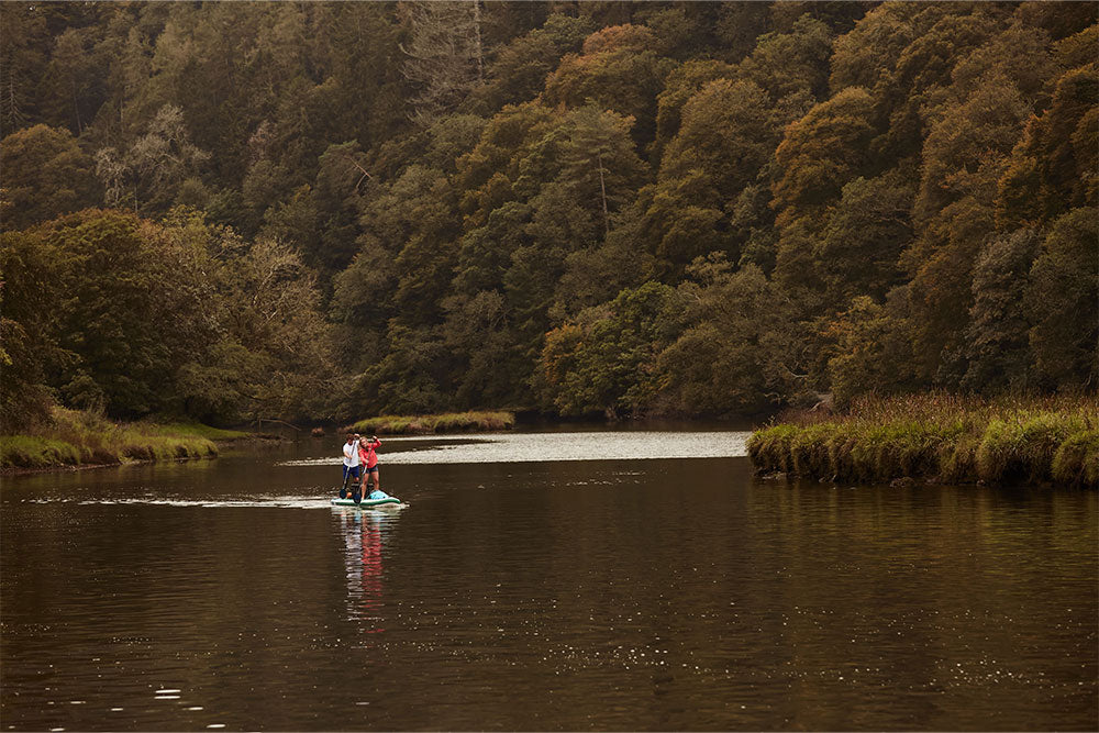 couple paddling in a lake surrounded by woodland