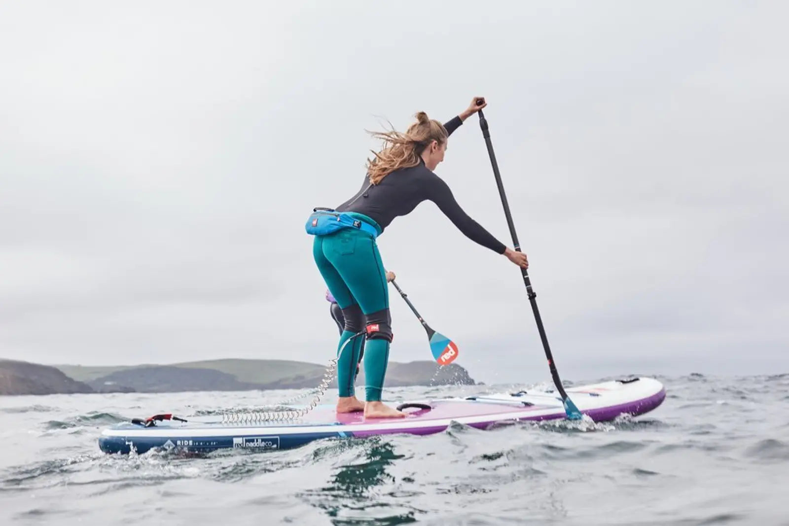 A woman paddleboarding on a choppy sea