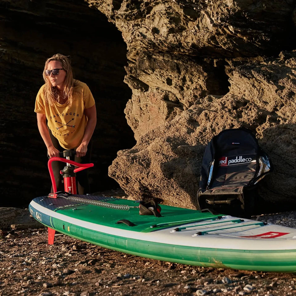 woman inflating Red Inflatable Paddle Board on a beach