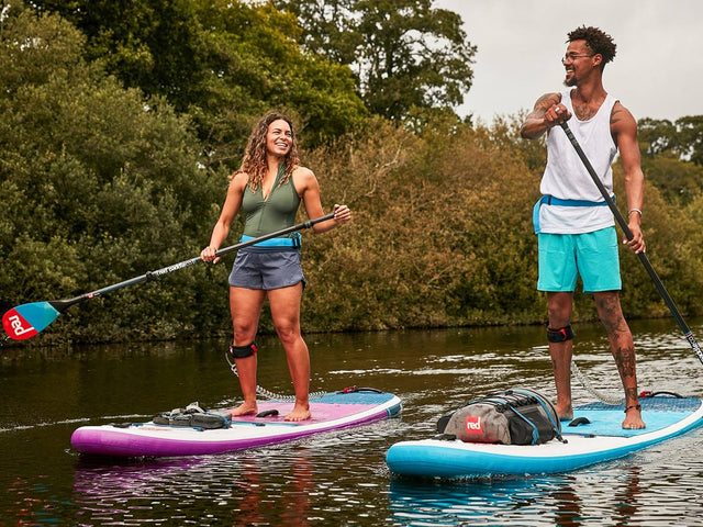 two people paddling alongside each other on Red inflatable paddle boards