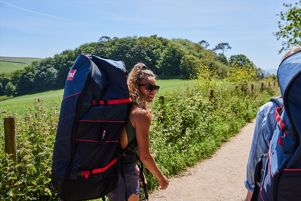 Woman walking through country lanes carrying Red Original ATB Board Bag