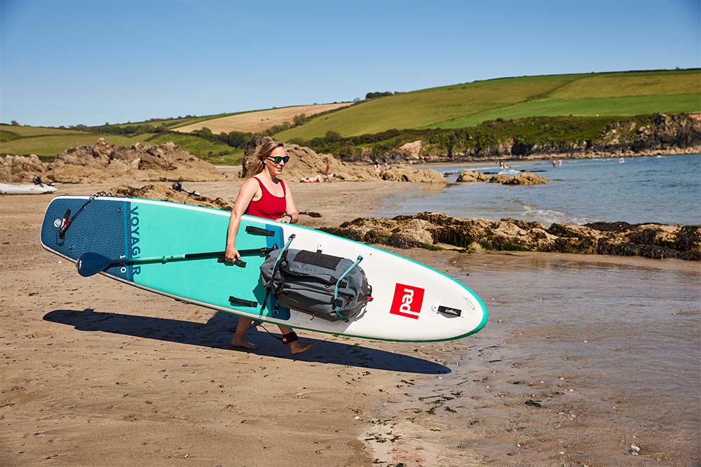 woman carrying paddleboard into the sea