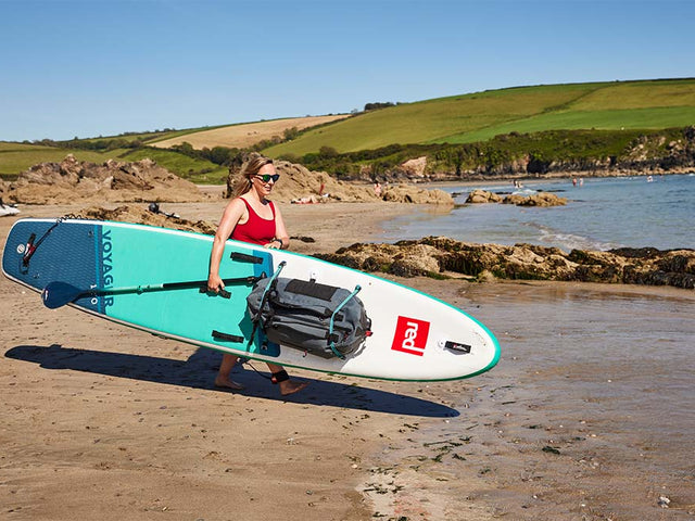 woman carrying paddleboard into the sea
