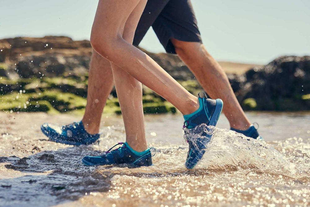 Two people walking through water wearing Red Original Aqua Shoes