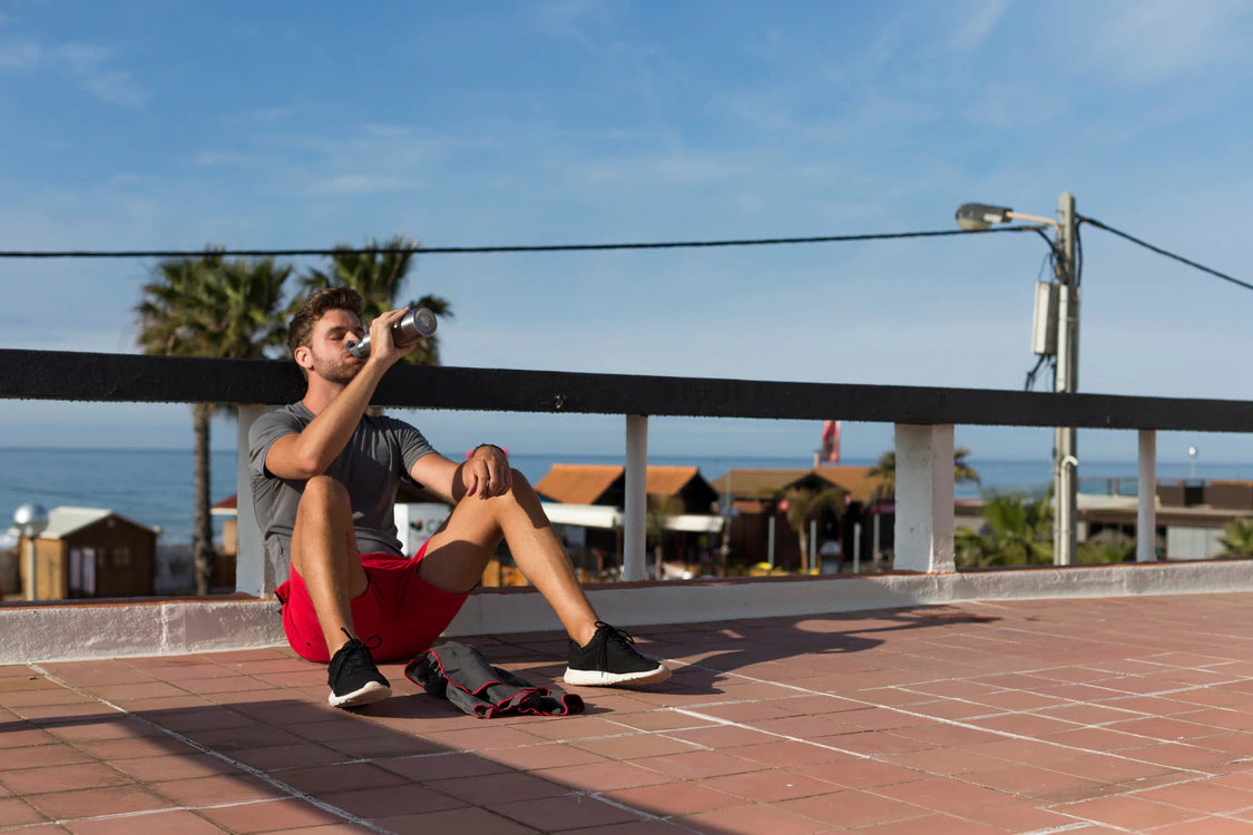 man sat on floor drinking from water bottle after run