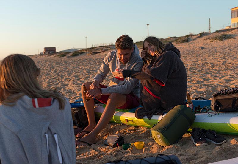 man and woman sat on paddleboard on beach