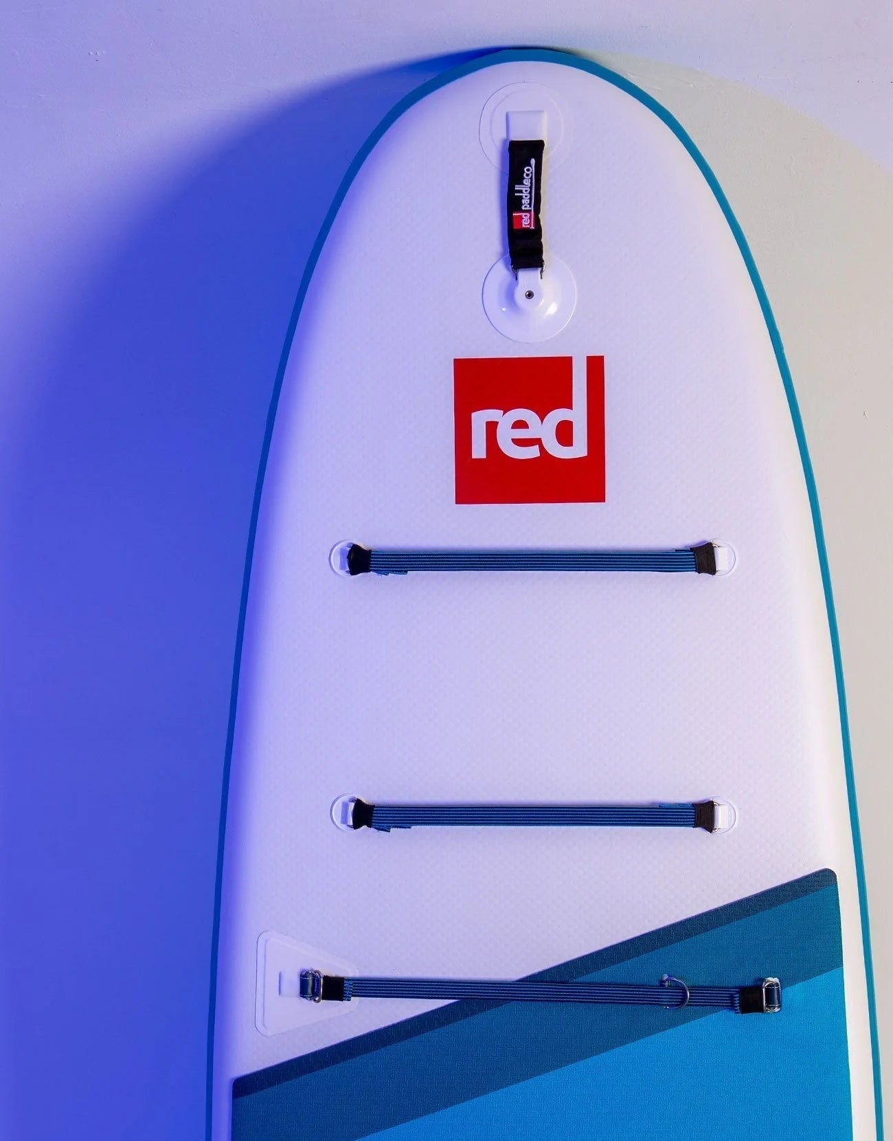 A paddleboard leaning against the ball with the red logo on the paddleboard