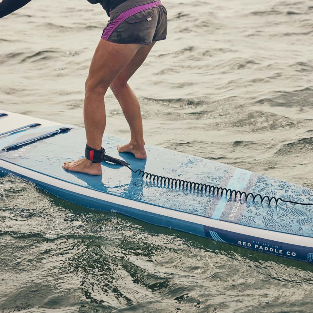 A woman paddleboarding with the ankle strap attached