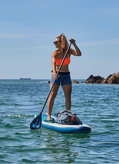 A woman paddleboard in the sun in the sea