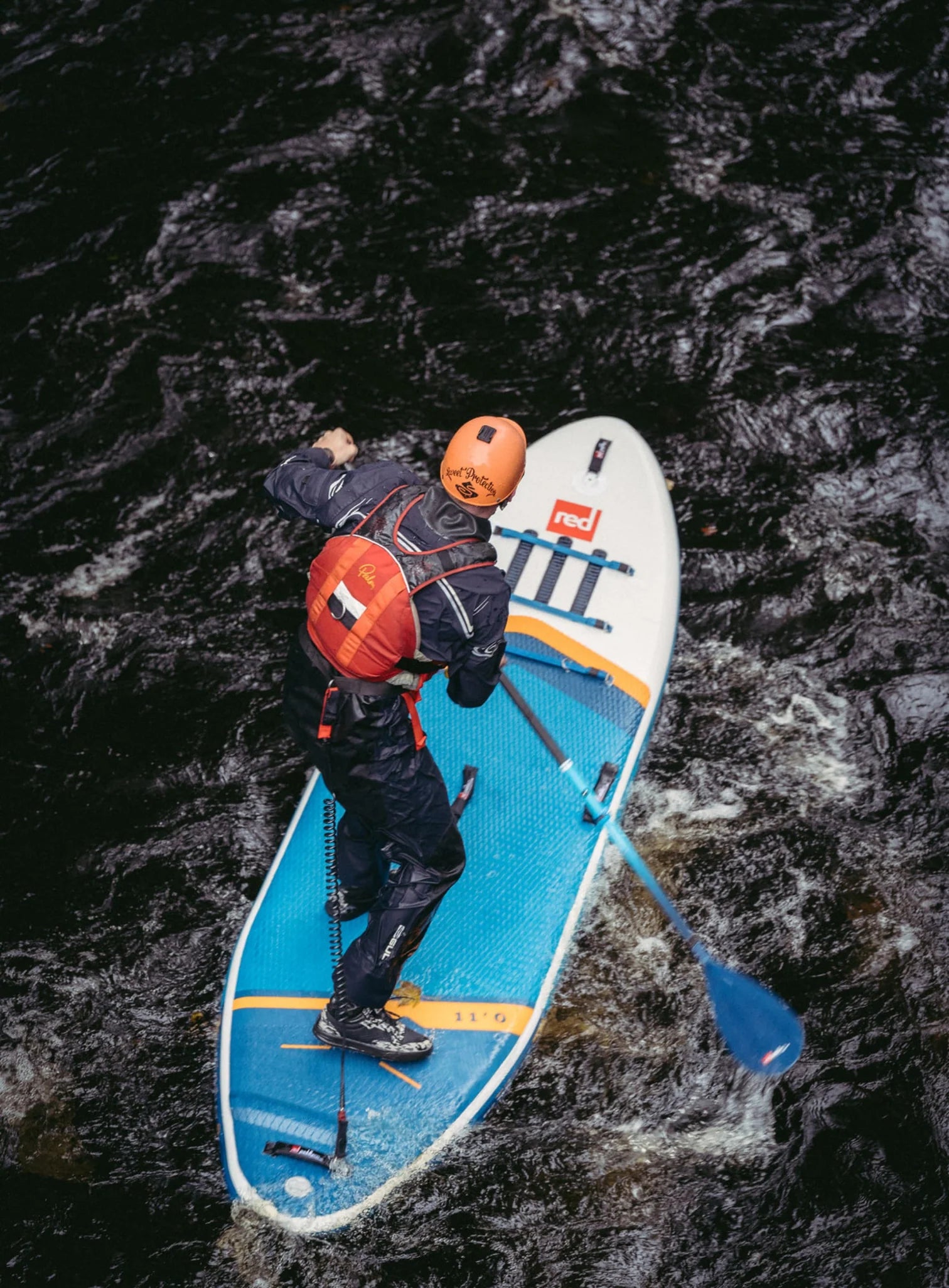 A man stand up paddleboarding on a river